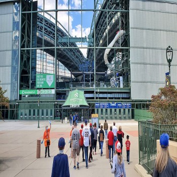 Fans cross a pedestrian bridge toward AmFam Field's eastern entrance