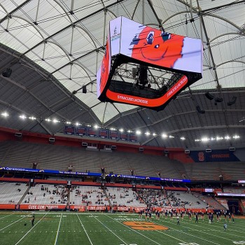 Interior of the renovated JMA Wireless Dome at Syracuse University in February 2022, featuring large center-hung scoreboards.
